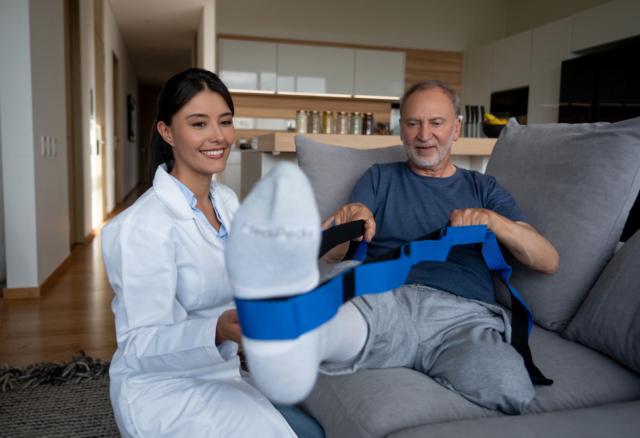 Doctor helping a disabled senior man at home with his physiotherapy